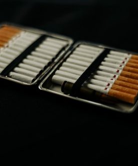 An open cigarette case filled with cigarettes, placed on a dark surface, conveying a mood of smoking and lifestyle.